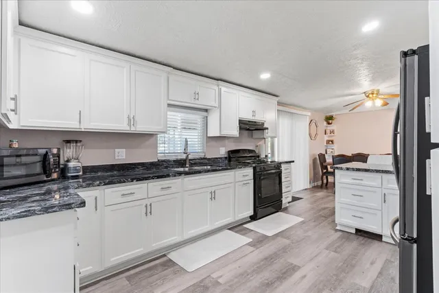 a kitchen with granite countertop a sink stove and cabinets