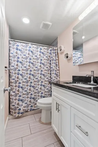 a bathroom with a granite countertop toilet a sink and a shower