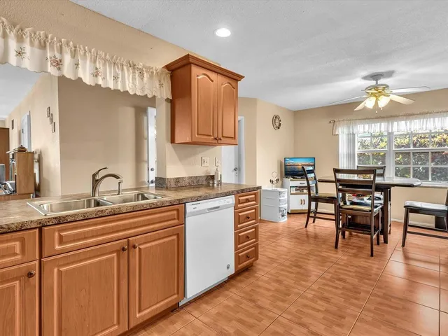 a kitchen with stainless steel appliances granite countertop a stove top oven a sink a dining table and chairs with wooden floor