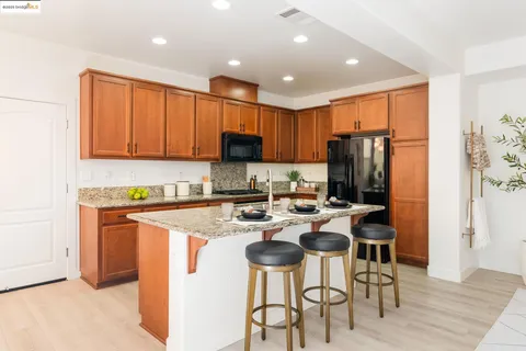 a kitchen with stainless steel appliances granite countertop a refrigerator a stove a sink a dining table and chairs with wooden floor