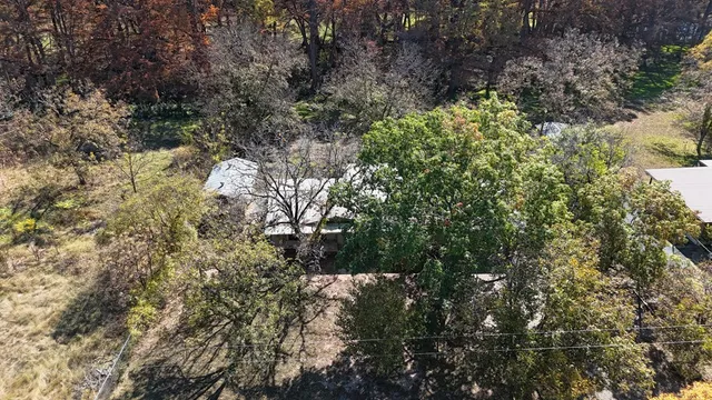 an aerial view of a house with a yard and large trees