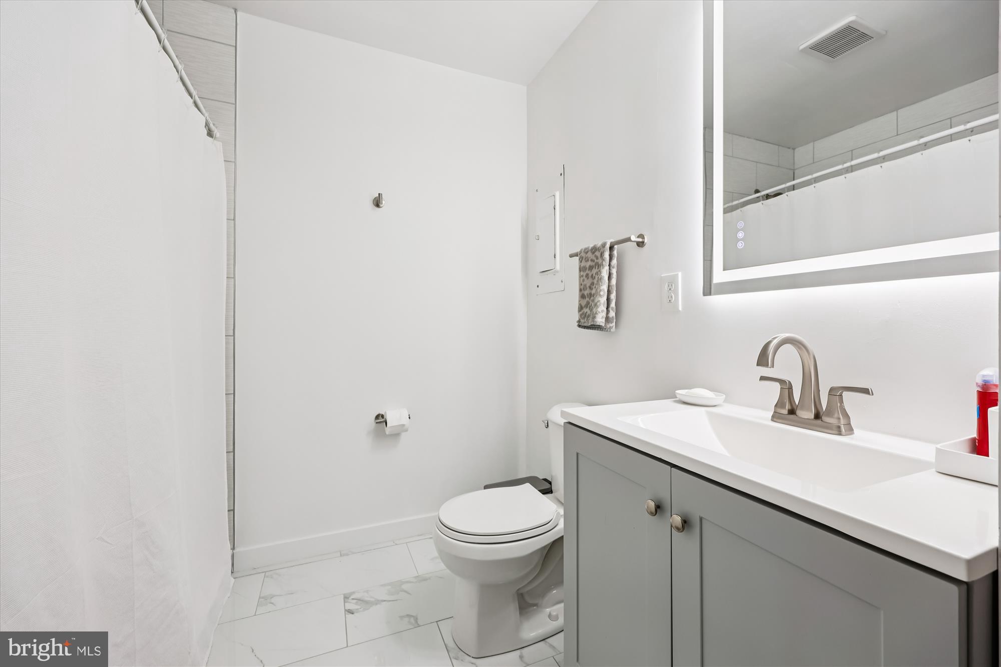 8313 Shady Spring Drive Gaithersburg, MD 20877 - Photo 15 of 30 a bathroom with a toilet a sink a mirror and vanity