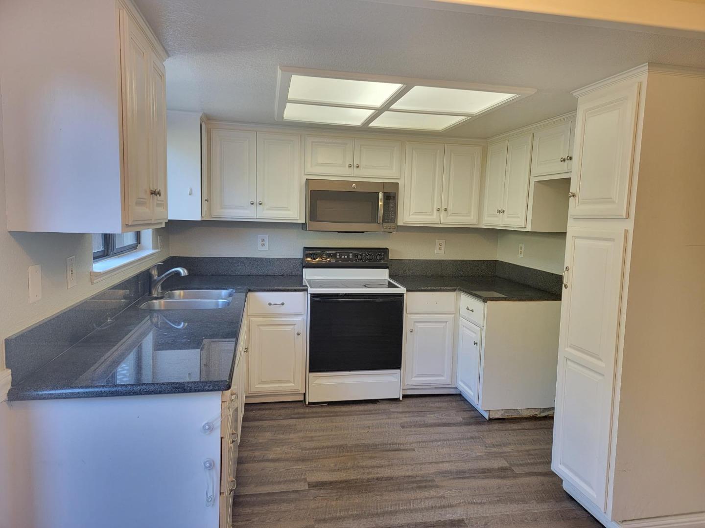 801 Nash Road, Unit A9 Hollister, CA 95023 - Photo 3 of 13 a kitchen with granite countertop white cabinets and white appliances