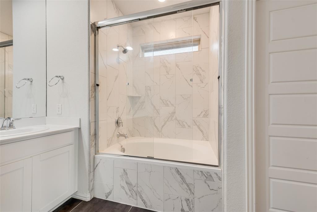 628 Ansley Way Allen, TX 75013 - Photo 13 of 20 Tub-shower combination featuring a frameless glass enclosure and white-veined tile surround