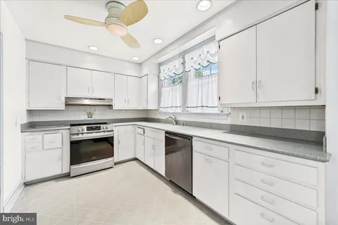 a kitchen with white cabinets and refrigerator