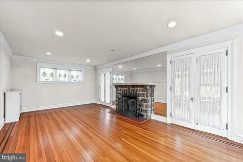 an empty room with wooden floor fireplace and windows