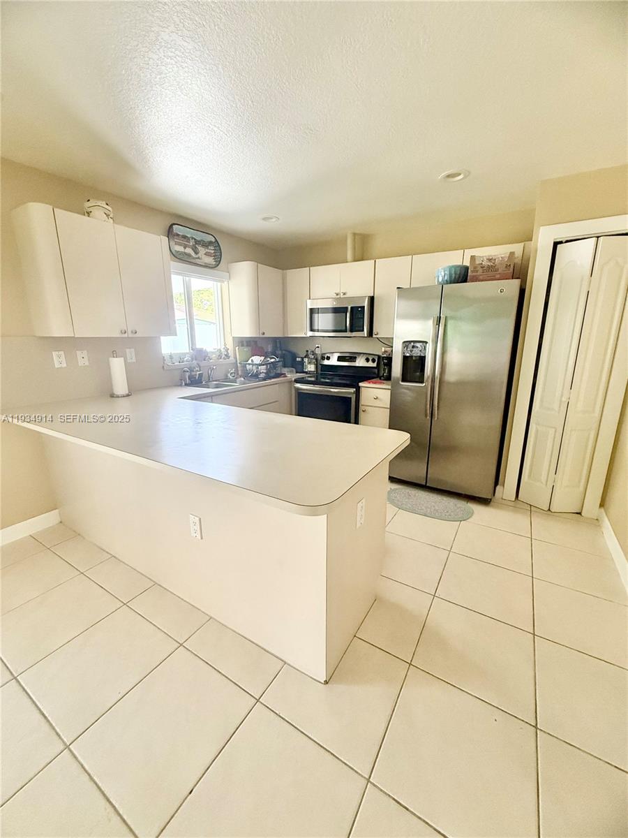 13267 Southwest 277th Terrace Homestead, FL 33032 - Photo 7 of 23 a kitchen with granite countertop a refrigerator and a stove top oven