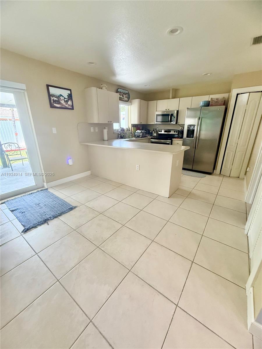 13267 Southwest 277th Terrace Homestead, FL 33032 - Photo 8 of 23 a kitchen with stainless steel appliances kitchen island granite countertop a refrigerator sink and cabinets