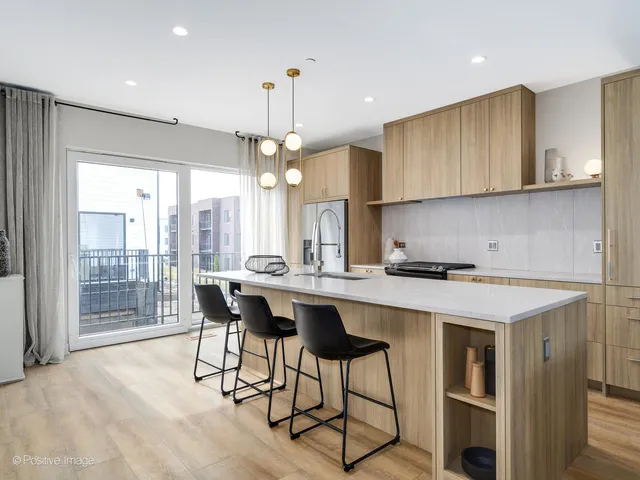 a kitchen with stainless steel appliances granite countertop a stove a refrigerator a sink dishwasher a dining table and chairs with wooden floor