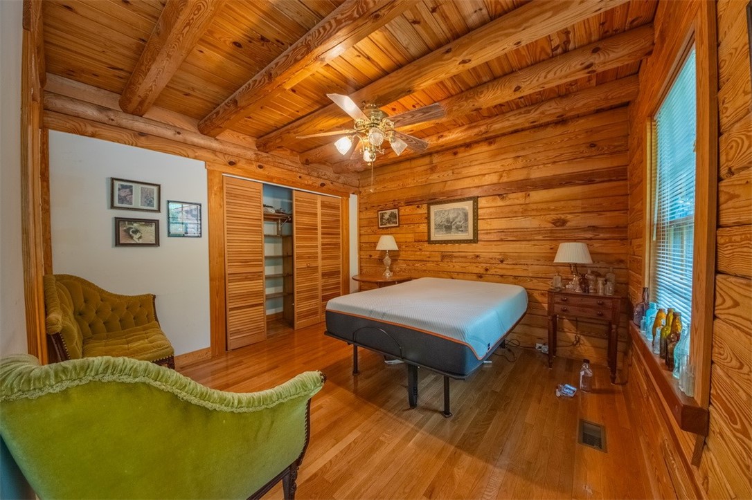 846 Twiggs Ferry Road Hartfield, VA 23071 - Photo 12 of 28 Bedroom with wood finished floors, a closet, ceiling fan, a wood ceiling with exposed beams, and wooden walls