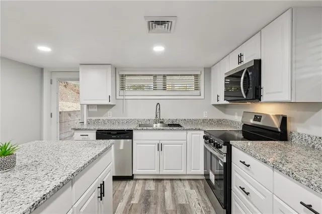 a kitchen with stainless steel appliances granite countertop a sink stove microwave and cabinets