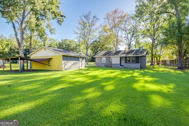 a view of a house with a big yard and large tree