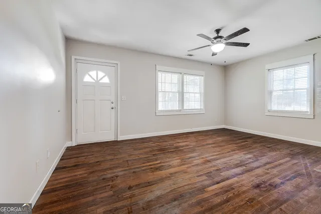 a view of an empty room with wooden floor and a window