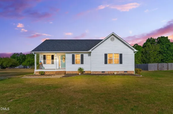 a front view of house with yard and trees in the background