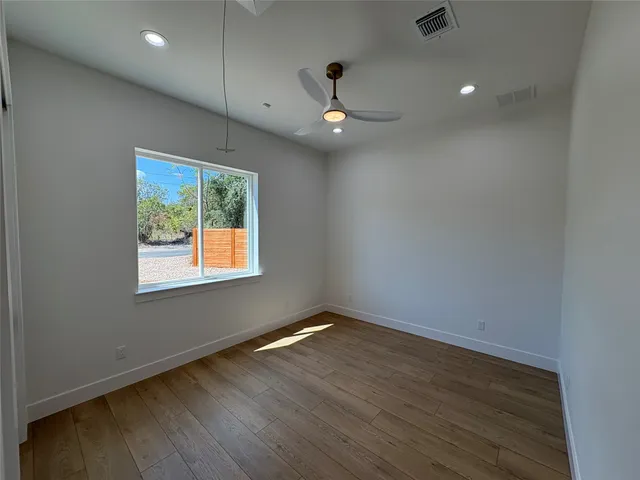 a view of empty room with wooden floor and window