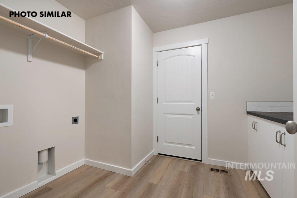 1645 Haystack Emmett, ID 83617 - Photo 28 of 33 Utility room featuring wood-finish flooring, a built-in shelf with hanging rod, and white cabinetry with a dark countertop and subway tile backsplash