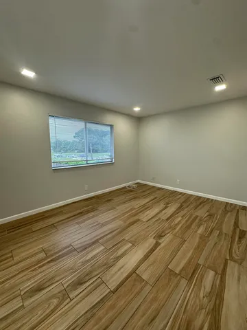 an empty room with wooden floor and windows