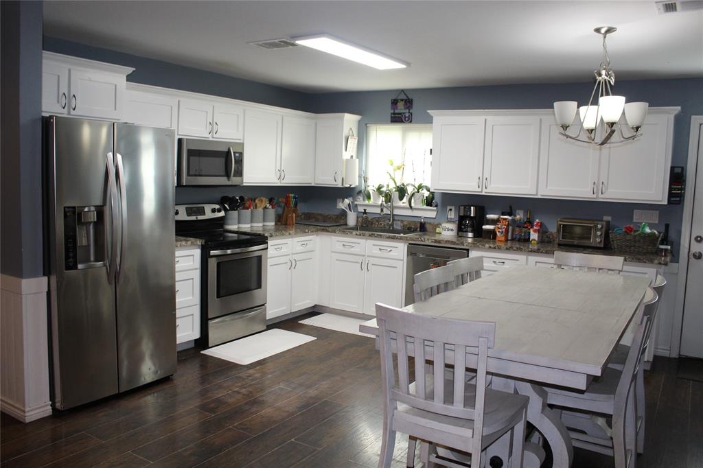402 Cleveland Street Bailey, TX 75452 - Photo 5 of 17 Kitchen with stainless steel appliances, a chandelier, dark wood-type flooring, and white cabinetry