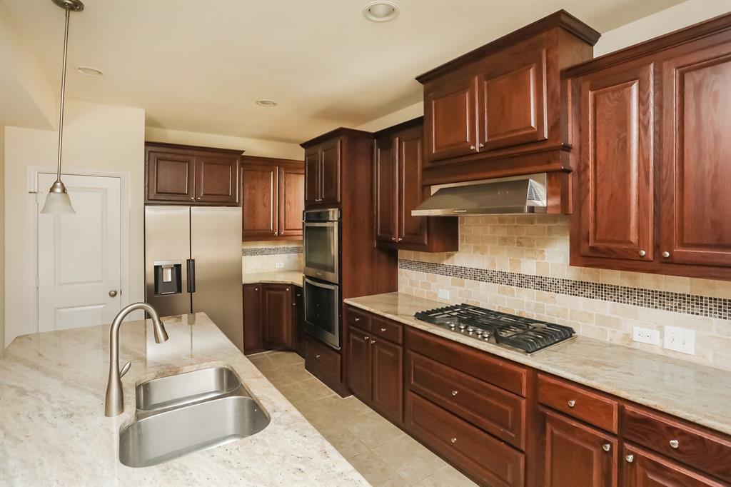 1014 Longhill Way Forney, TX 75126 - Photo 6 of 15 a kitchen with granite countertop wooden cabinets and stainless steel appliances