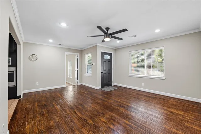 a view of an empty room with a window and wooden floor