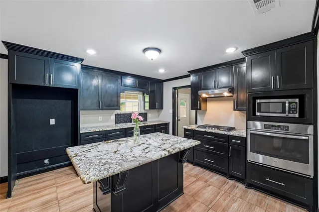 a kitchen with kitchen island granite countertop wooden cabinets and a refrigerator
