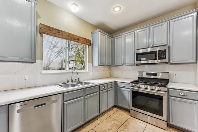 a kitchen with stainless steel appliances granite countertop a sink stove refrigerator and cabinets