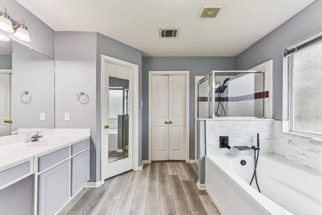a spacious bathroom with a double vanity sink a mirror and a bathtub