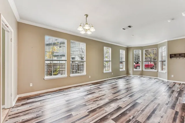 a view of an empty room with a window and wooden floor