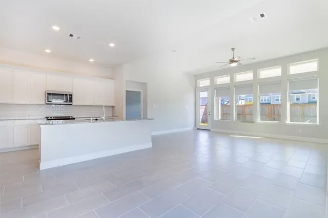 a large white kitchen with kitchen island a stove a sink and cabinets