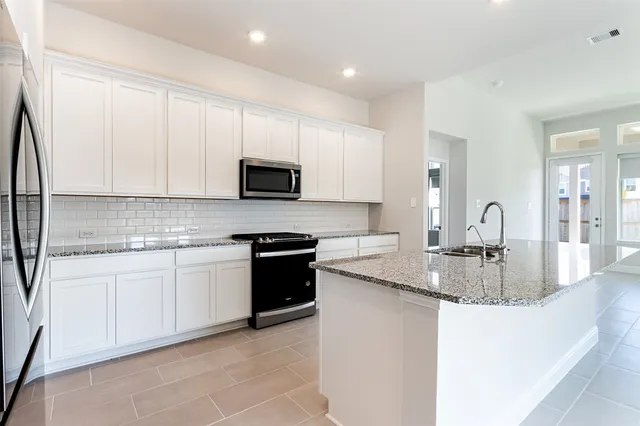 a kitchen with kitchen island granite countertop a sink a stove and cabinets