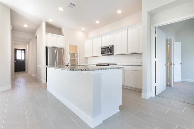 a kitchen with kitchen island white cabinets and refrigerator