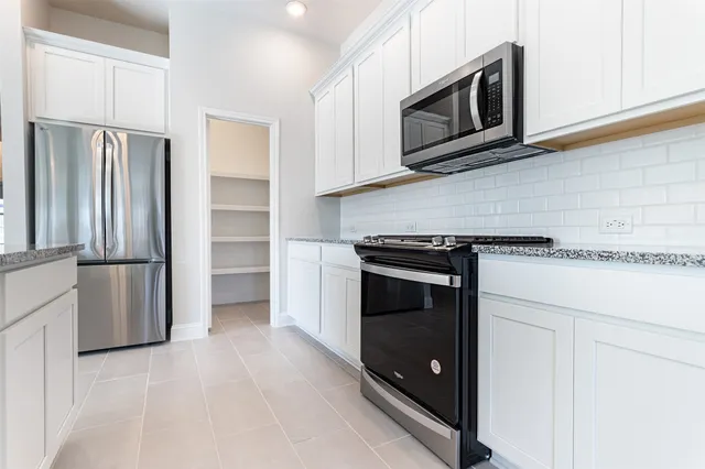 a kitchen with stainless steel appliances granite countertop a refrigerator stove and microwave