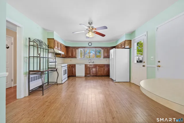 a living room with furniture and a kitchen with wooden floor