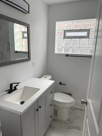 a bathroom with a sink a toilet and a window