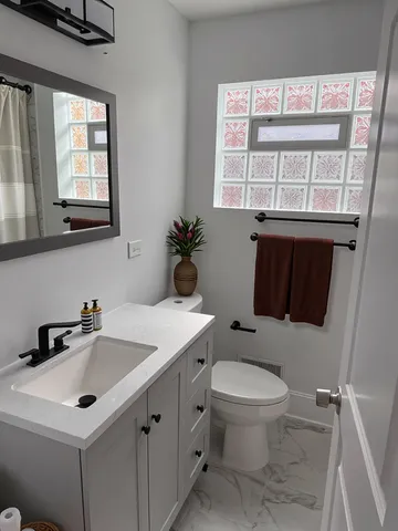 a bathroom with a sink a toilet and a window