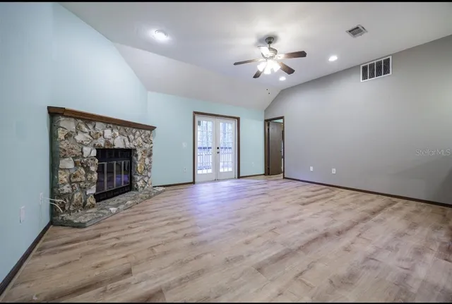 a view of an empty room with chandelier fan and fire place