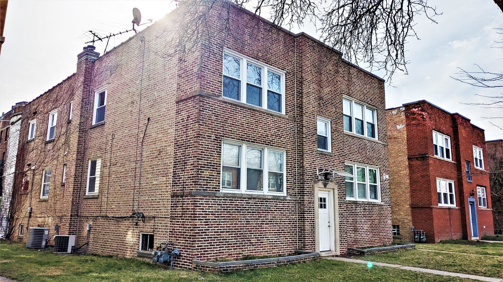a front view of a brick building next to a yard