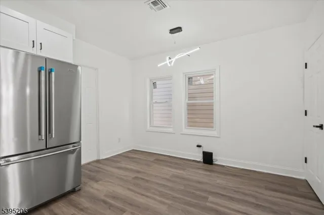 a view of empty room with wooden floor and window