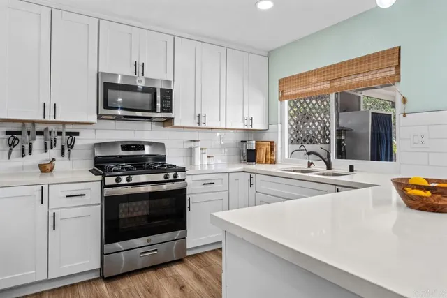 a kitchen with stainless steel appliances granite countertop grey cabinets a stove a sink and dishwasher
