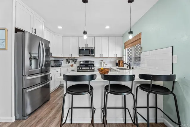 a kitchen with stainless steel appliances kitchen island a table chairs refrigerator and microwave