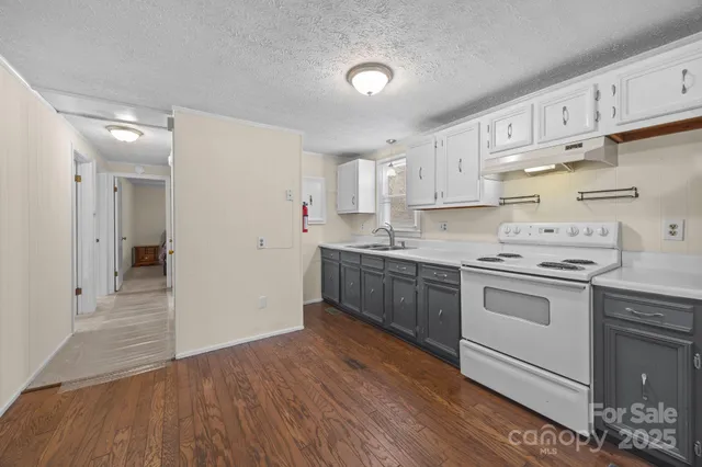 a kitchen with stainless steel appliances granite countertop a sink cabinets and a wooden floor