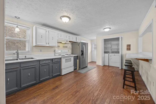 a kitchen with stainless steel appliances kitchen island wooden floors and white cabinets