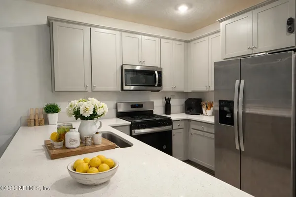 a kitchen with stainless steel appliances granite countertop a stove refrigerator and microwave