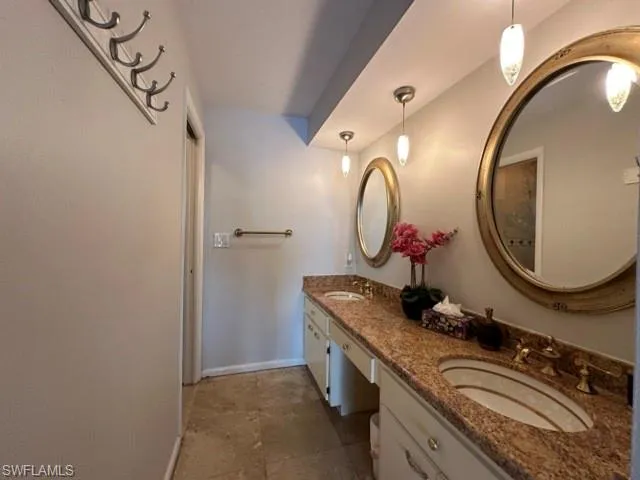 a bathroom with a granite countertop double vanity and a mirror