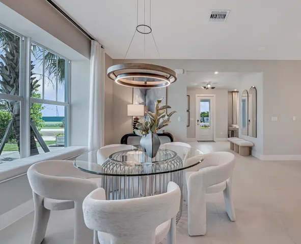 a large white kitchen with lots of white furniture a sink a table and chairs