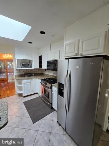 a kitchen with granite countertop a refrigerator a sink a stove top oven and cabinets