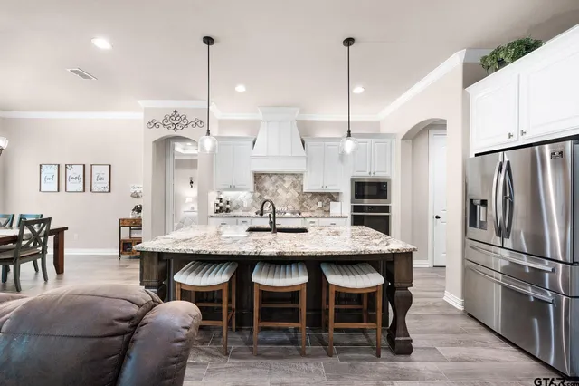 a kitchen with stainless steel appliances kitchen island granite countertop a table chairs and a refrigerator