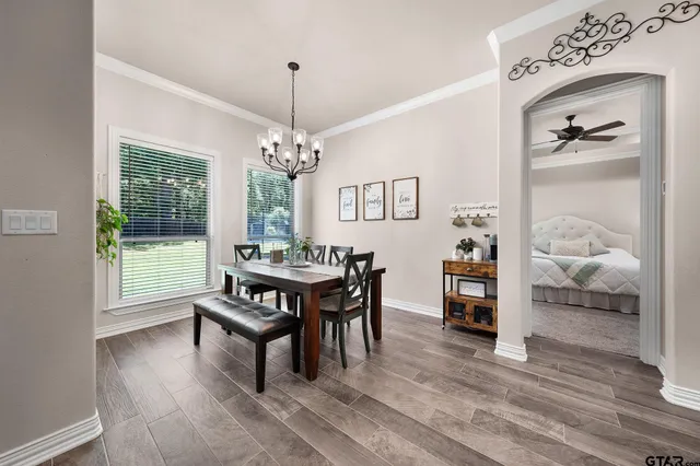 a dining room with wooden floor a chandelier a wooden table and chairs