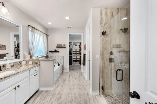 a large bathroom with a granite countertop double vanity sink a mirror and a shower