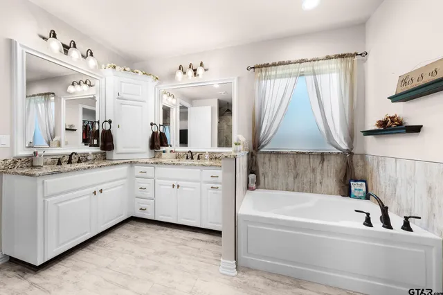 a bathroom with a granite countertop sink mirror and a bathtub